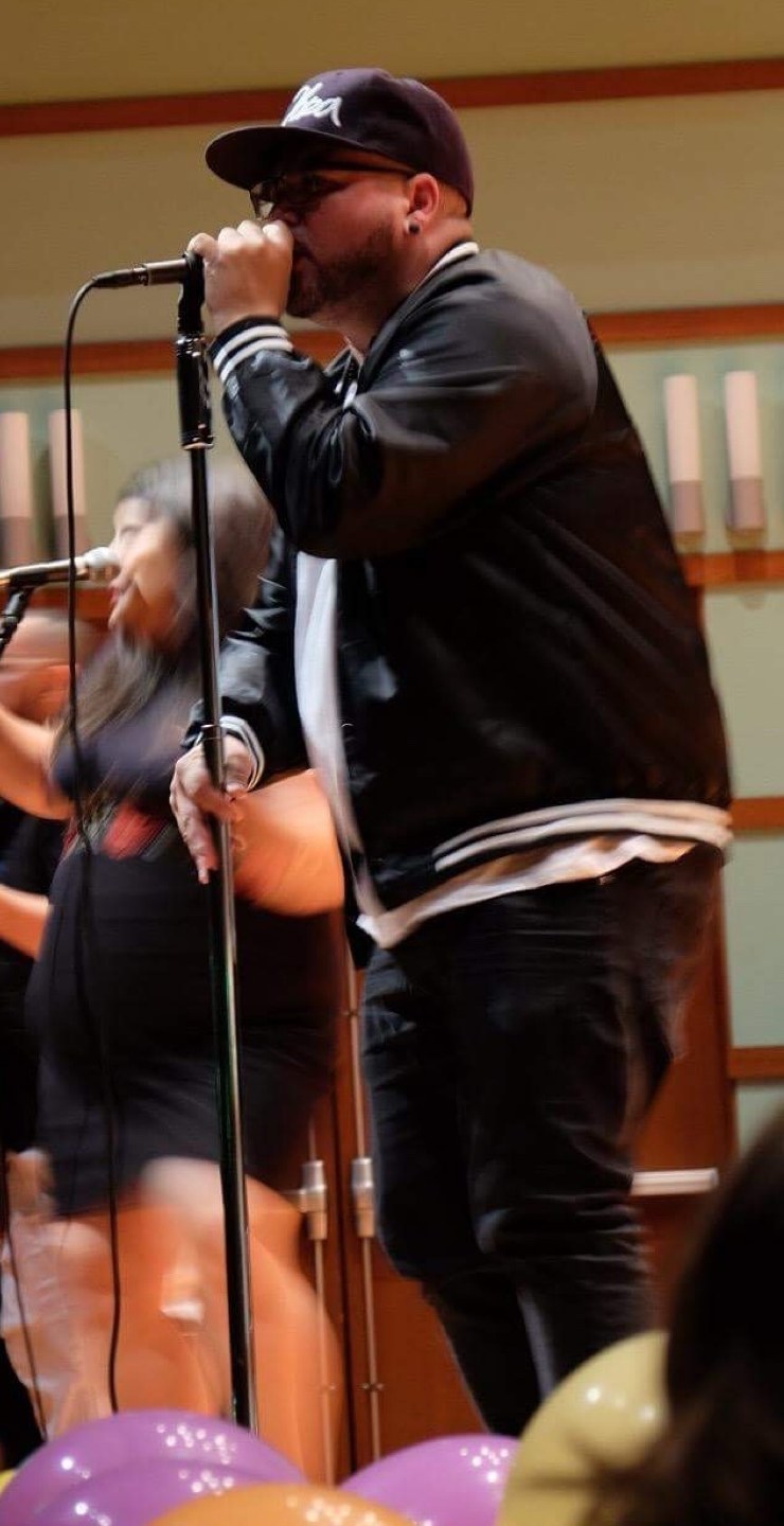 La Obra vocalist singing at the mic